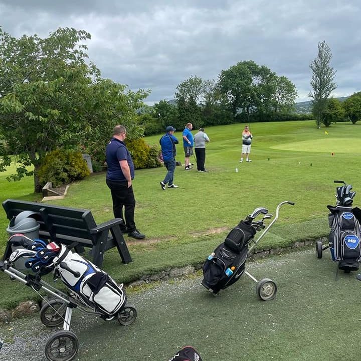 Golfers with bags ready at the hole on a golf course